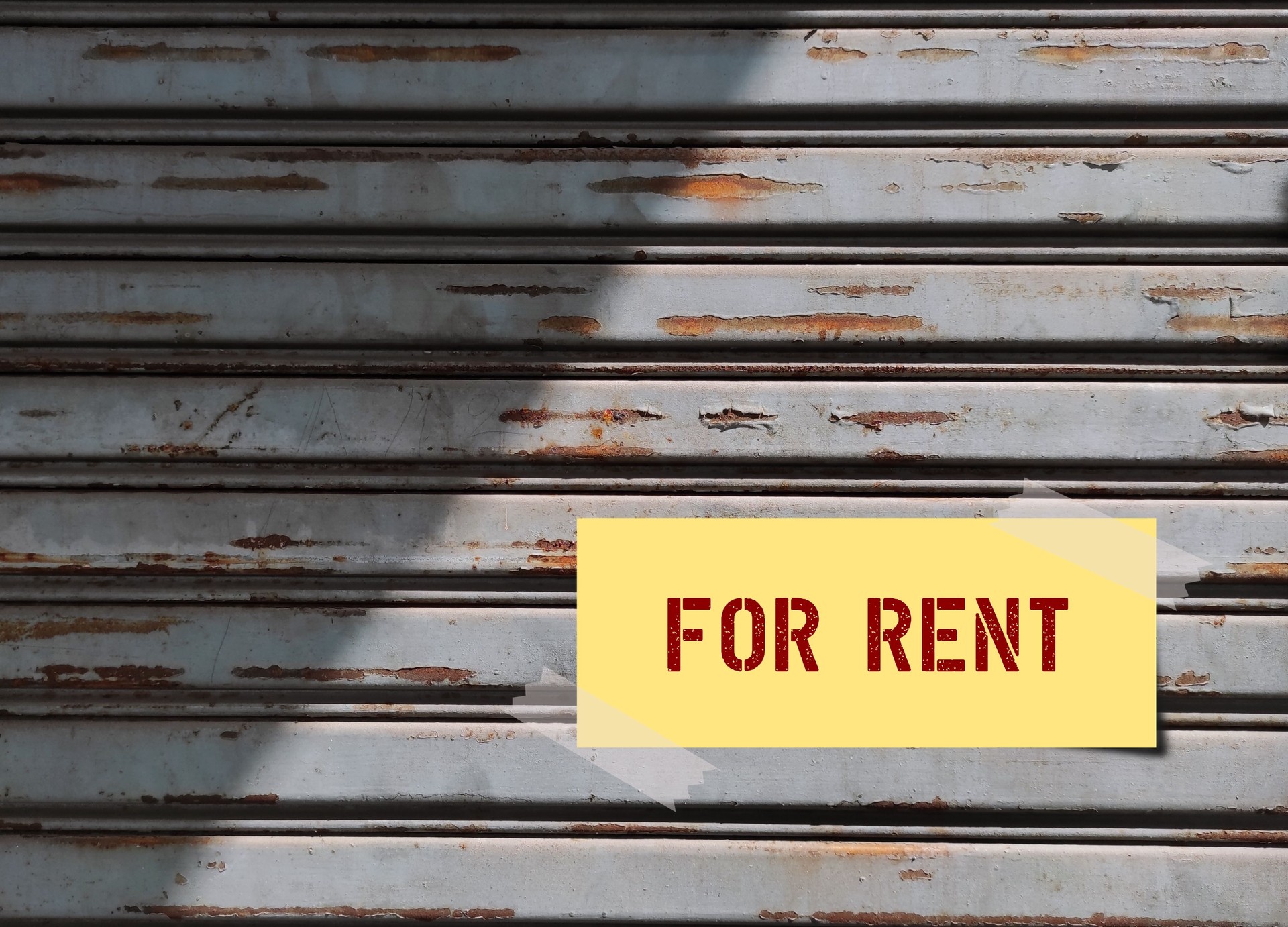 Old grunge metal door with text on note written FOR RENT, concept of a property owner or  landlord want to giving a house on rent, to boost passive income or to make regular earning from asset