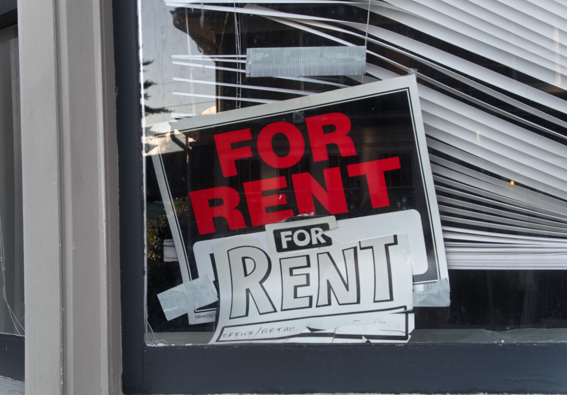 A 'For Rent' sign in the corner of a window
